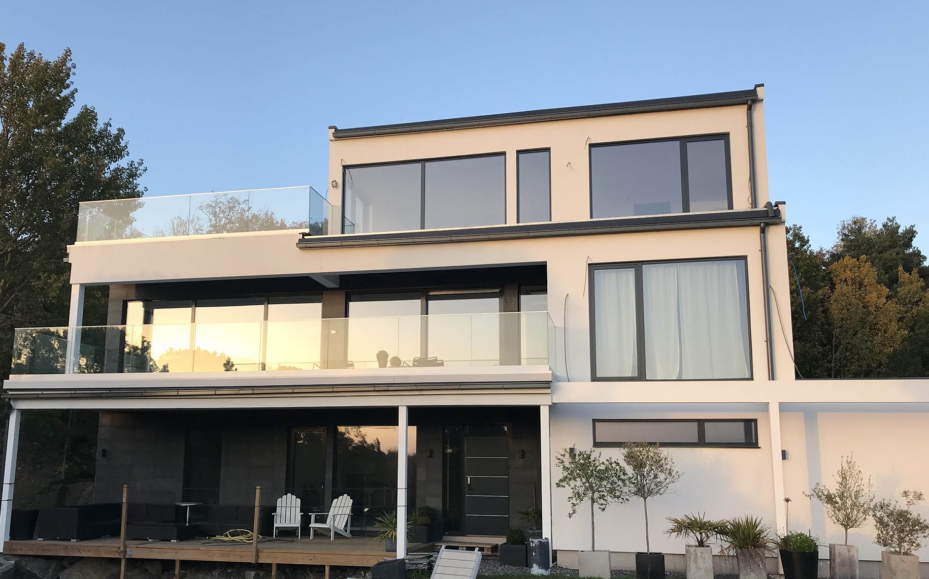 Villa med glasräcken på terrass och takterrass i kvällsljus